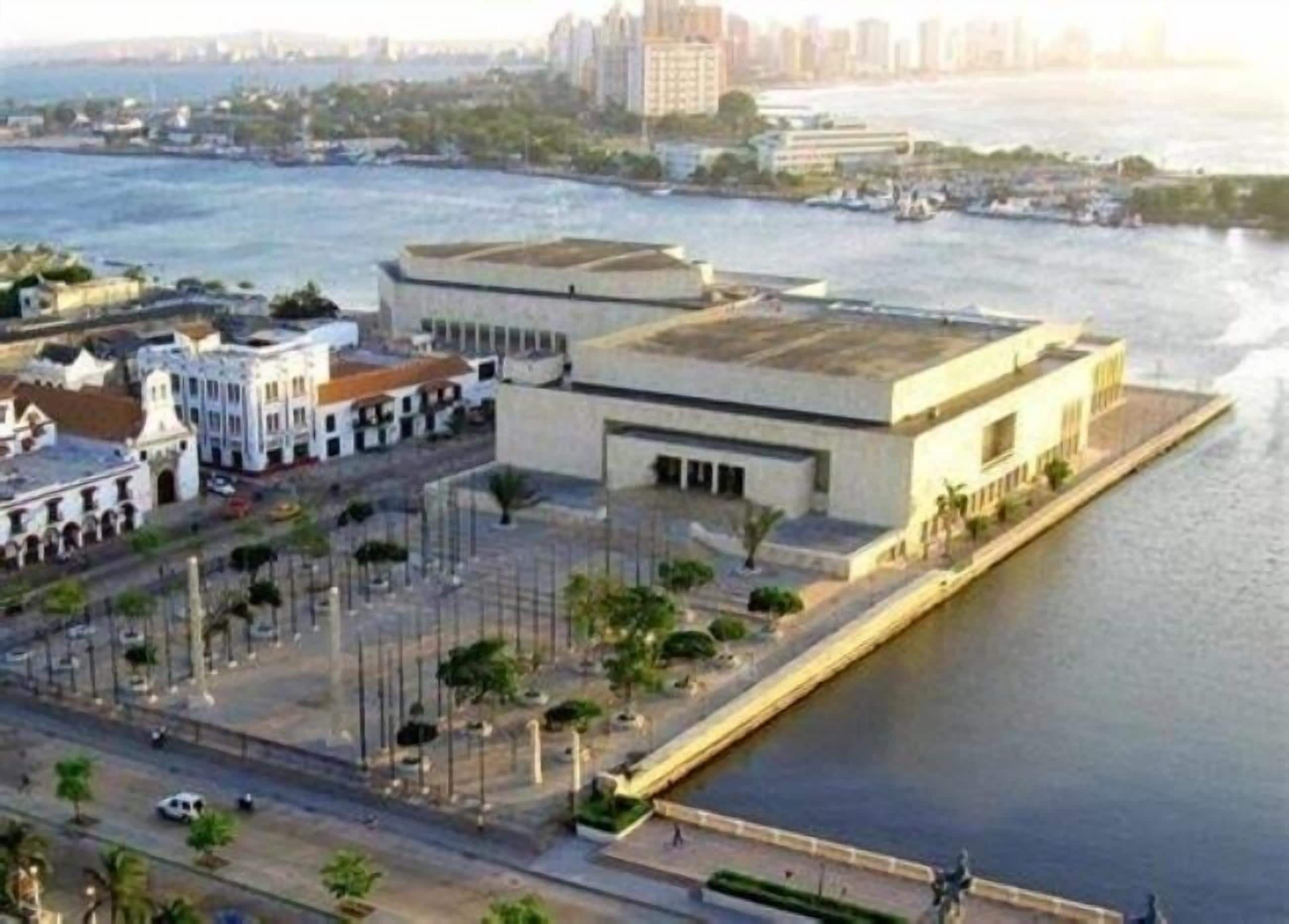 An aerial view of a waterfront area with buildings, a road, and a body of water.