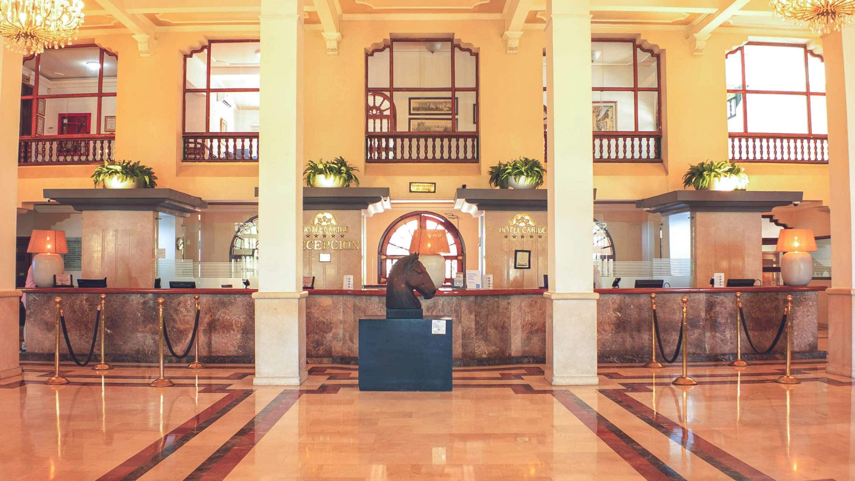 A hotel lobby with marble flooring, a reception desk, and a chandelier.