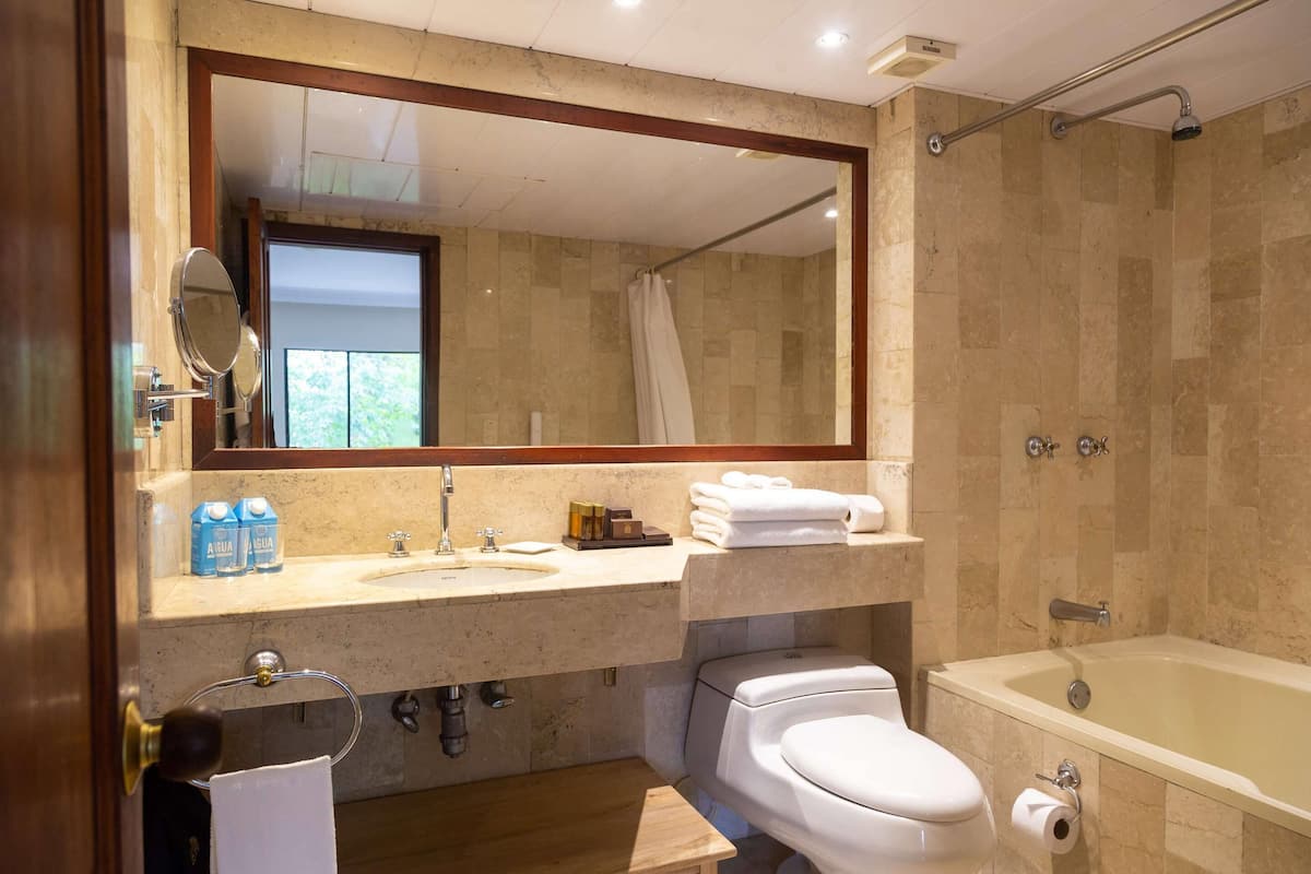 Een moderne badkamer met een grote spiegel, een badkuip, een toilet en een wastafel.