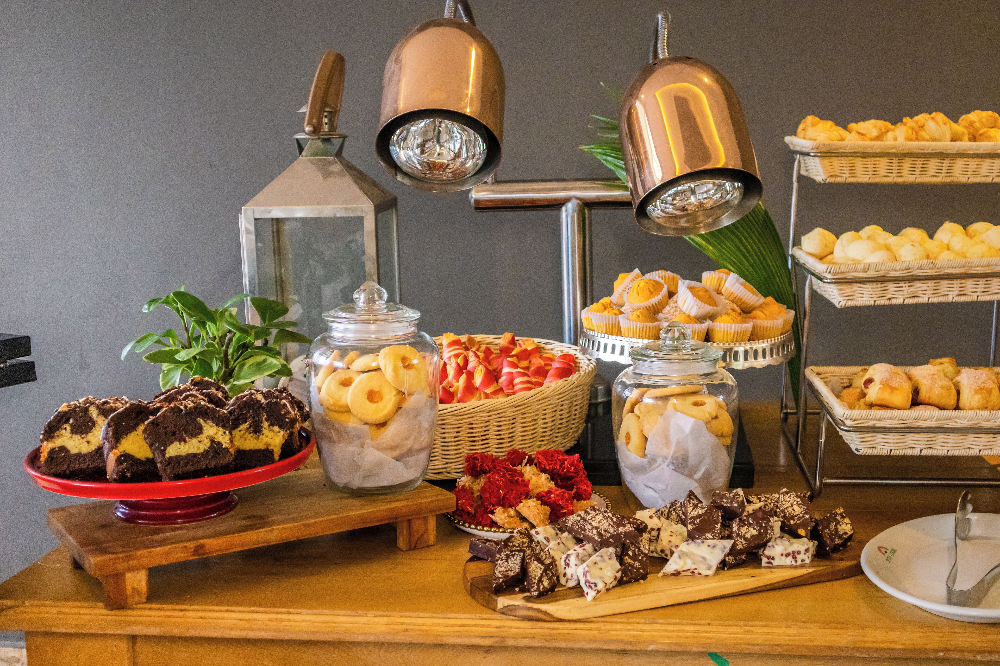 A buffet table with various baked goods, including muffins and pastries, arranged on a wooden table with metal stands.