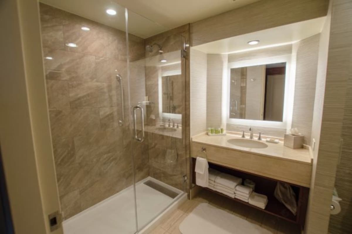 A modern bathroom with a glass-enclosed shower, a vanity with a mirror, and a towel rack.