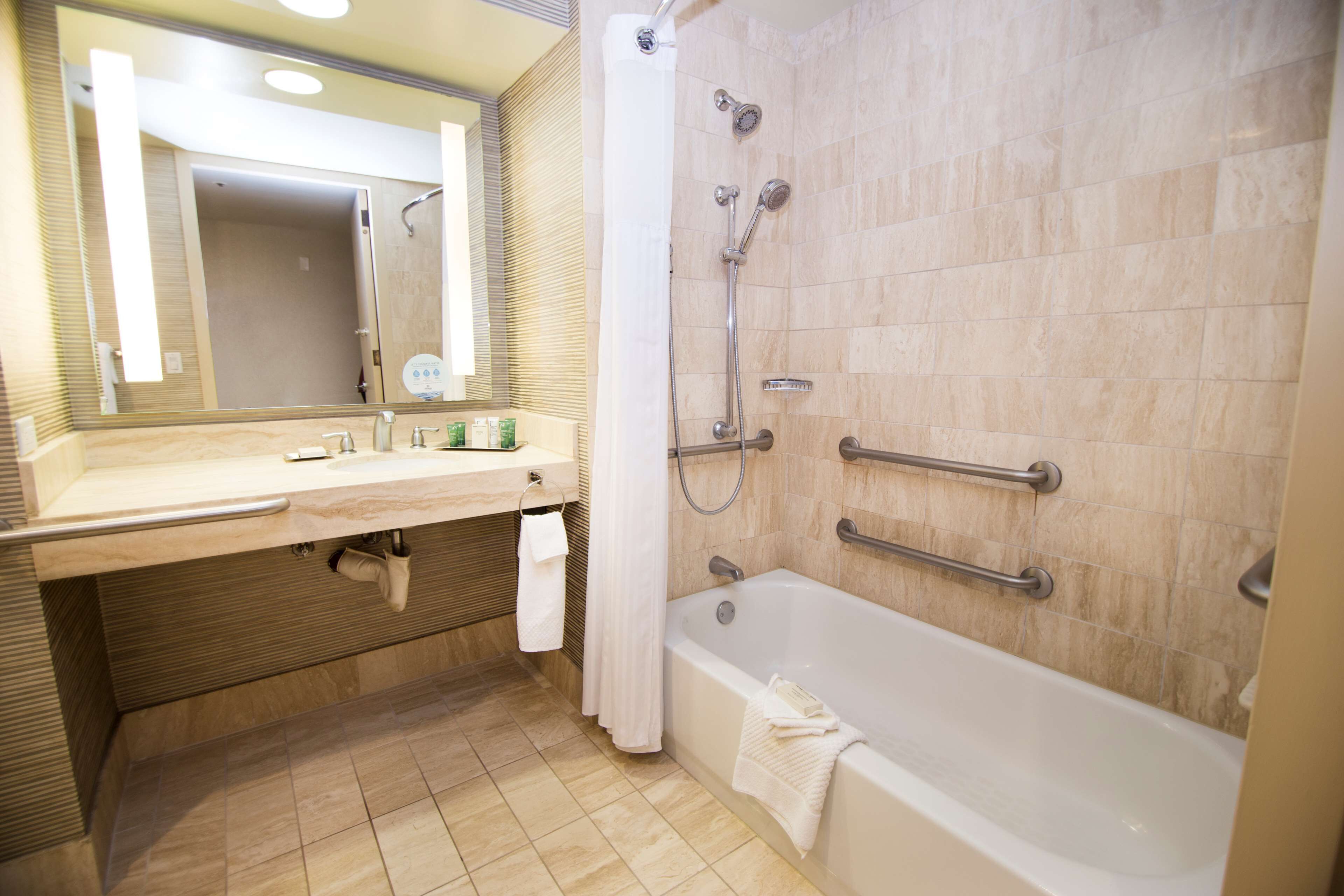 A bathroom with a bathtub, a shower, a sink with a mirror, and a towel hanging on the wall.