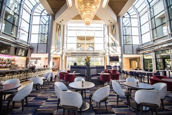 A spacious lobby with high ceilings, large windows, and a central seating area with a round table and chairs. at Hilton Los Angeles/Universal City