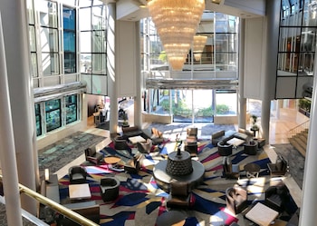 An indoor/outdoor lounge area with wicker furniture, potted plants, and a glass ceiling. at Hilton Los Angeles/Universal City