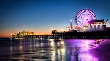 Une jetée avec une grande grande roue et un bâtiment illuminé au crépuscule.