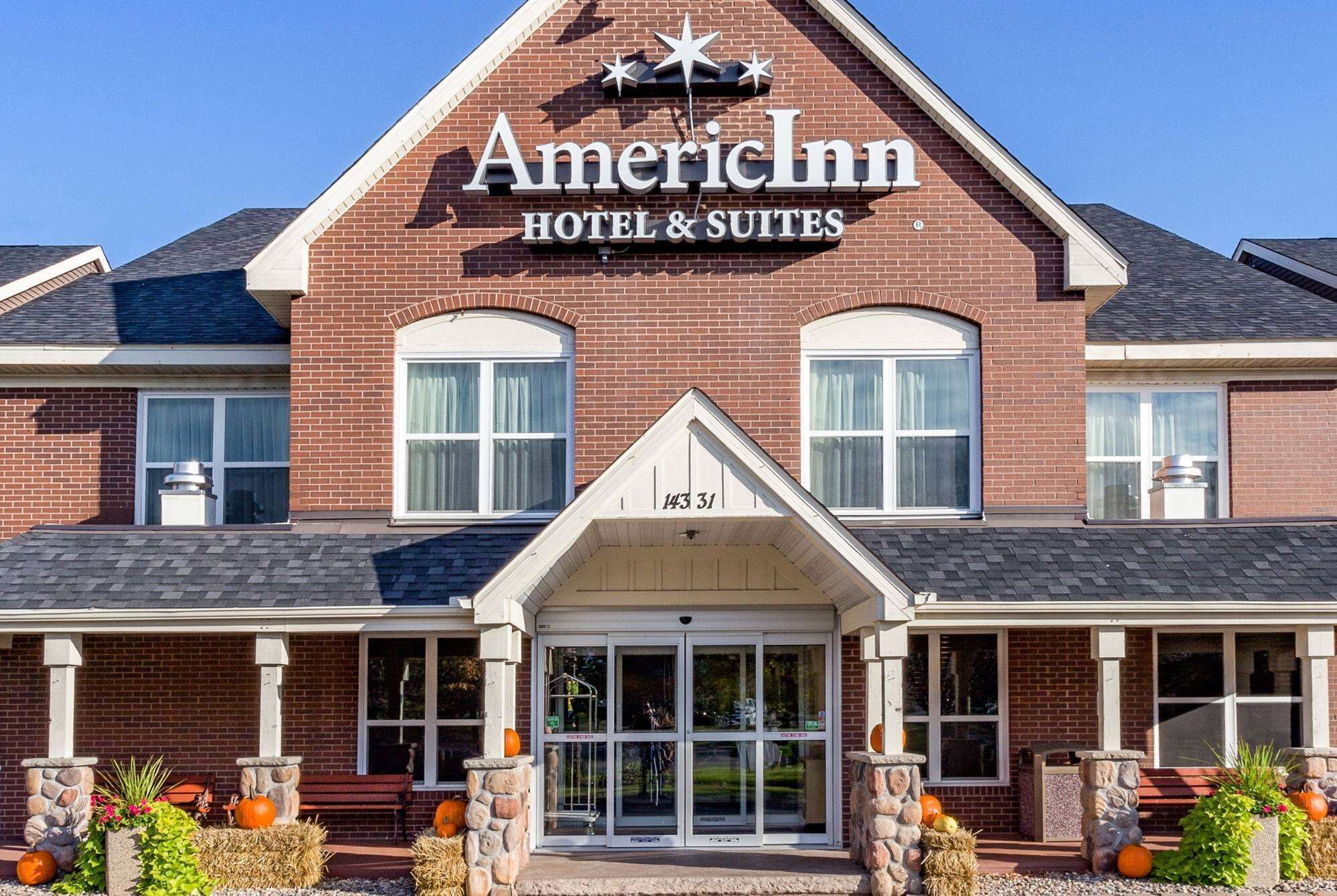 A brick building with a sign reading "American Inn Hotel & Suites" and a number "143 31" on the front.