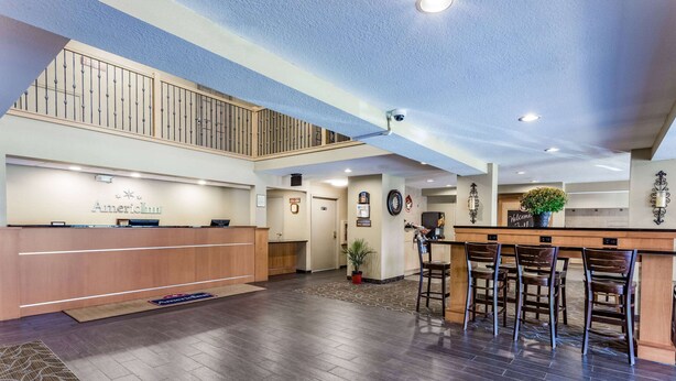 Un hall con mostrador de recepción, escalera y zona de bar.