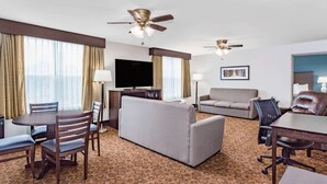 Habitación de hotel con comedor, sofá, televisor y dos ventiladores de techo.