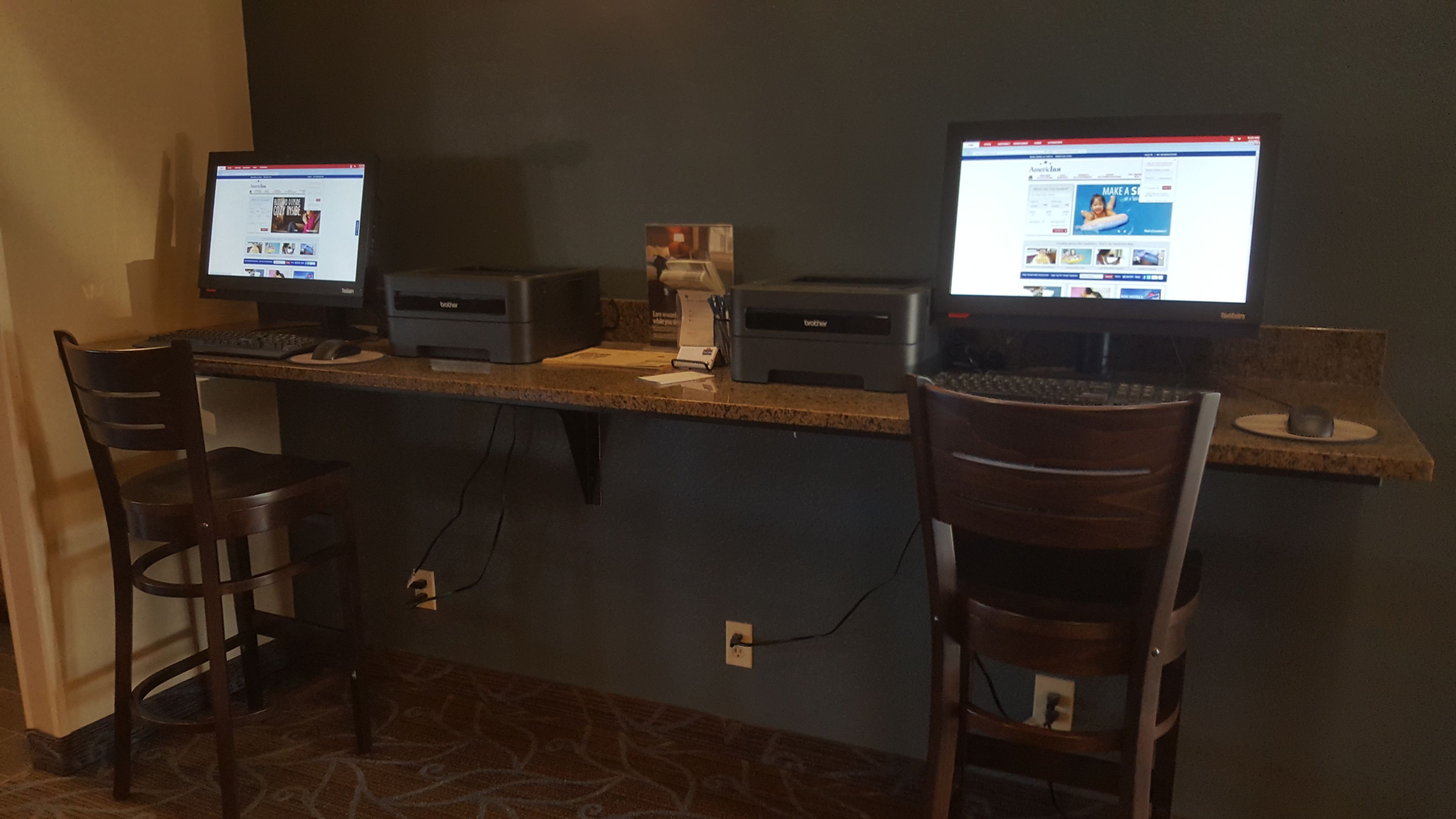 A workspace with two computers, a printer, and two chairs.