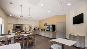 A spacious hotel lobby with a reception desk, seating area, and a kitchen in the background. - Clarion Pointe Sylva near Cherokee Area (Sylva)