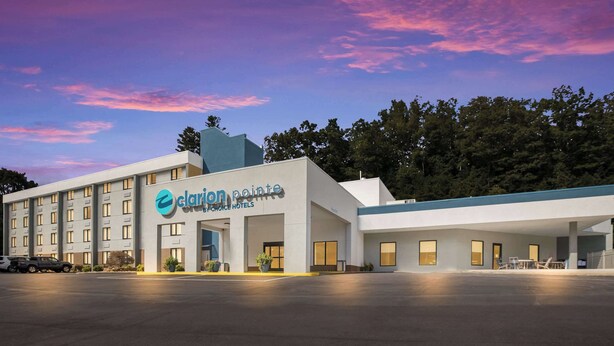 A hotel with a modern design, featuring a prominent logo and a spacious parking lot.