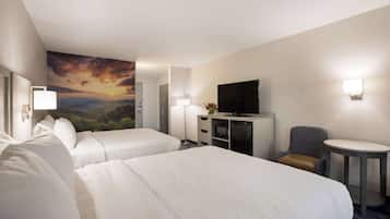 A hotel room with two beds, a TV, a desk, and a chair.