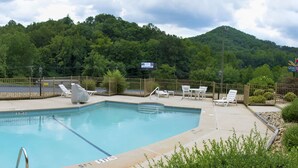A swimming pool with a fenced deck area, lounge chairs, and a lifeguard stand.