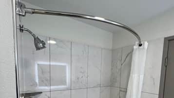 A modern bathroom with a glass shower enclosure, a walk-in bathtub, and marble tiles.