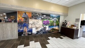 A reception area with a large mural, a reception desk, and a tiled floor. - Clarion Pointe Sylva near Cherokee Area (Sylva)