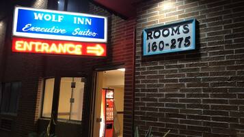 The exterior of the Wolf Inn, featuring a neon sign for the Executive Suites and a Rooms sign with a phone number.