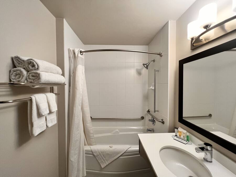 Ein modernes Badezimmer mit Badewanne, Dusche und Waschtisch mit Waschbecken und Spiegel.