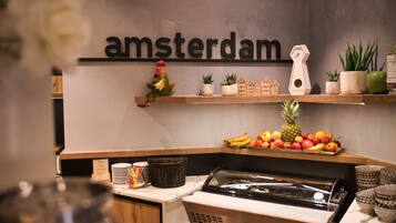 Et tekøkken med et skilt der står 'amsterdam', et frugtudvalg og en kaffemaskine.