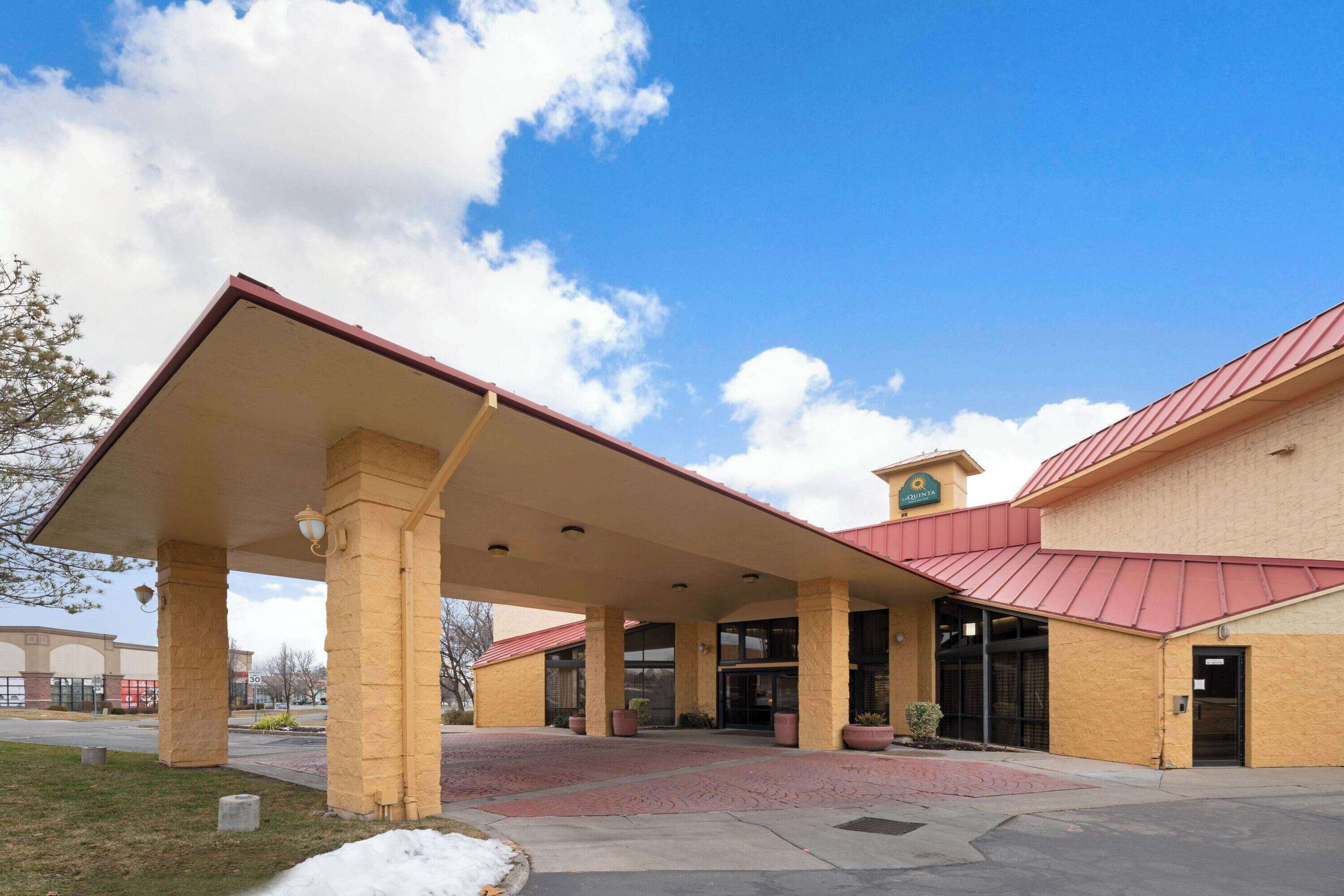 A hotel with a covered entrance, large windows, and a red roof.