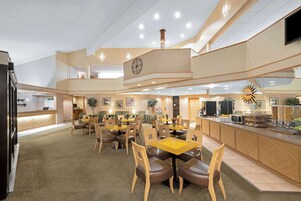 Eine großzügige Hotelhalle mit mehreren Gastronomiebereichen, einem Empfangsbereich und einer im Hintergrund erkennbaren Küche.