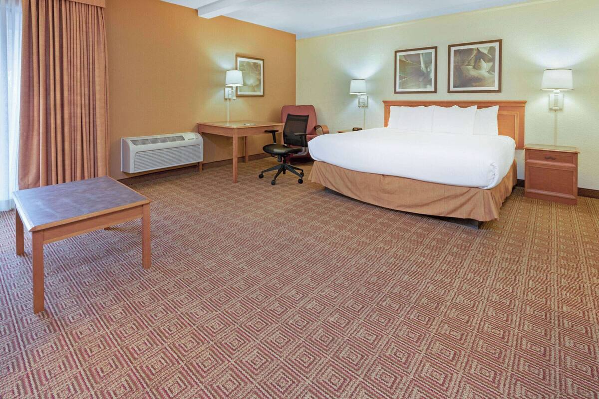 Ein Hotelzimmer mit Bett, Schreibtisch, Stuhl und einem kleinen Tisch.