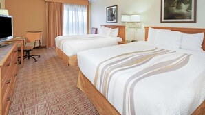 Een hotelkamer met twee bedden, een bureau met een computer, een stoel en een televisie.