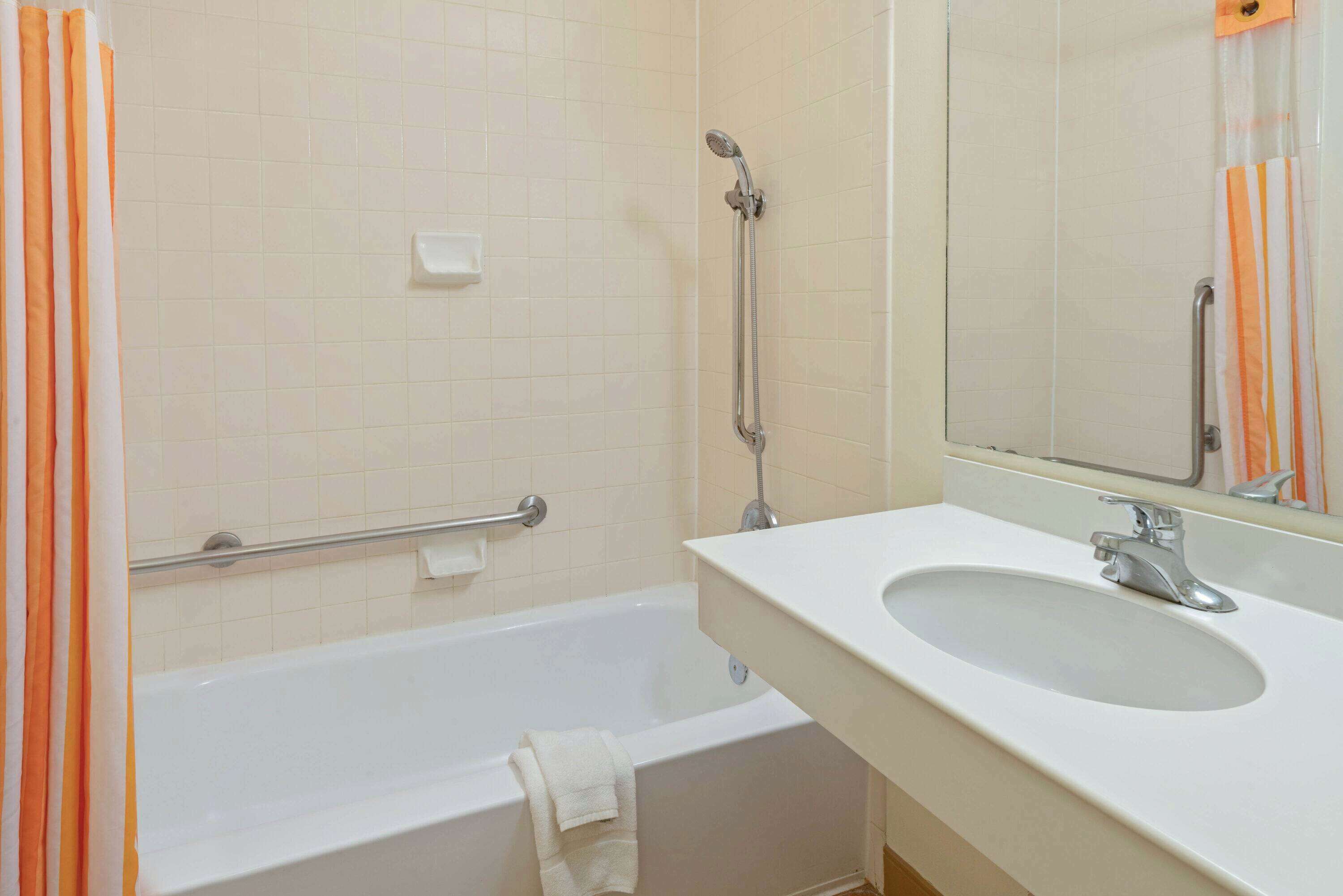 A bathroom with a bathtub, a sink, and a mirror.