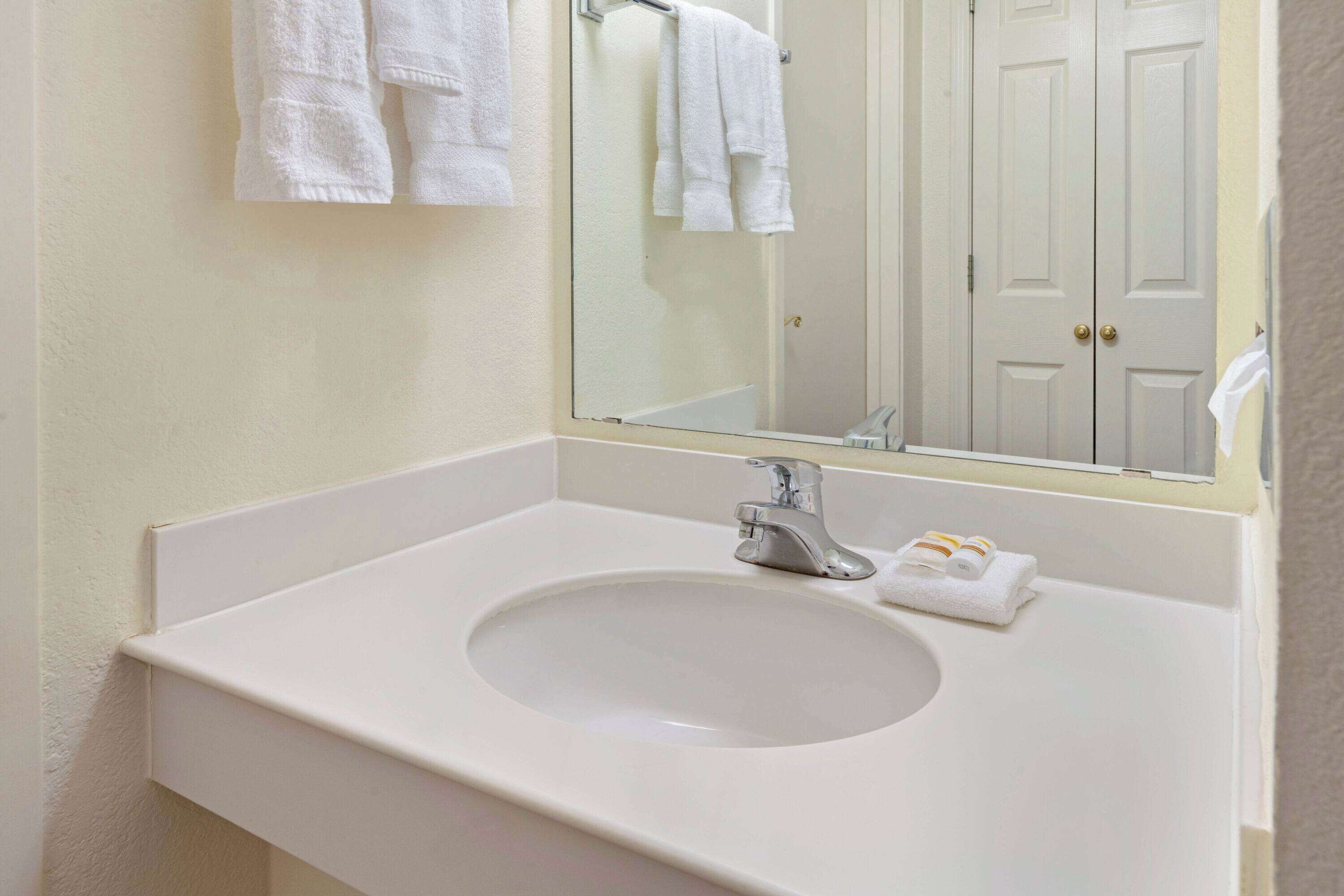 A bathroom with a white sink, a mirror, and a towel rack.