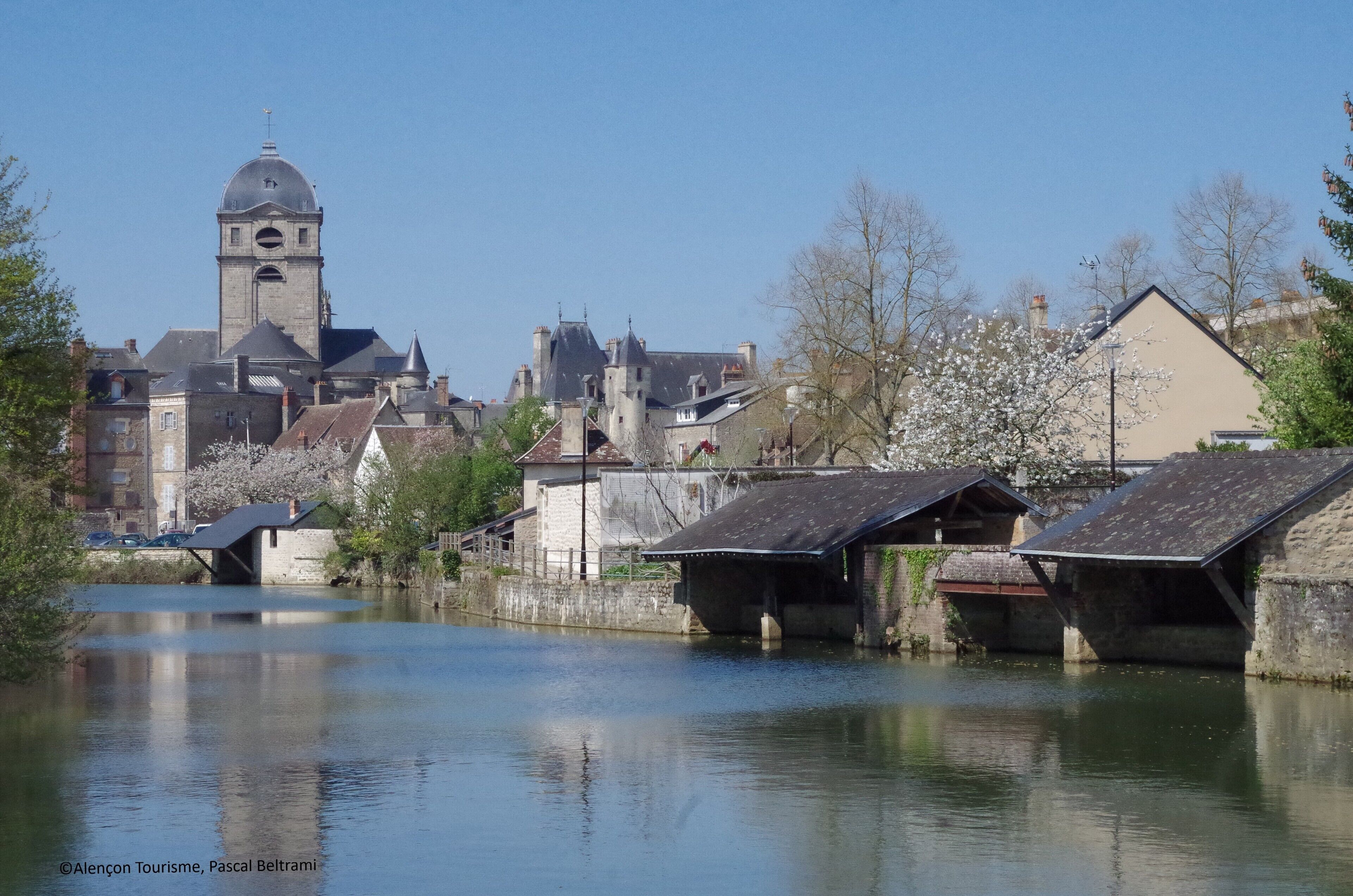 A riverside town with historic buildings, a prominent tower, and traditional bridges.