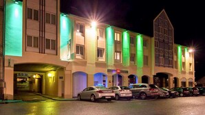 A hotel with a modern architectural design, featuring a central atrium with multiple levels of balconies and a parking area in front. - ibis Alencon (Alencon)