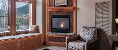 A cozy living room with a fireplace, a bench by the window, and a leather armchair.