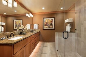 Une salle de bain moderne avec deux vasques, des meubles en bois et une cabine de douche en verre.