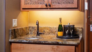 Una cocina con encimera de granito, un grifo de acero inoxidable, una botella de Veuve Clicquot Brut champagne y dos copas.