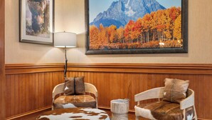 A room with two chairs upholstered in faux fur, a wooden bench, and a framed picture of a mountain landscape. - The Wyoming Inn of Jackson Hole (Jackson)