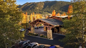 A lodge with a covered parking area, stone pillars, and a mountainous backdrop. - The Wyoming Inn of Jackson Hole (Jackson)