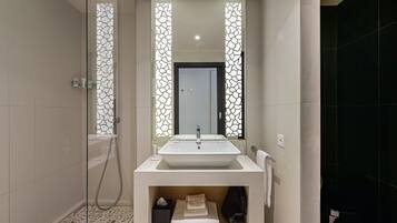 Un baño moderno con un espejo grande, un lavabo blanco y una zona de ducha.