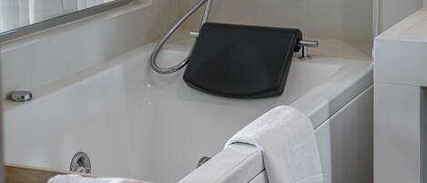 Une salle de bain moderne avec une baignoire, un tapis noir et un porte-serviettes.