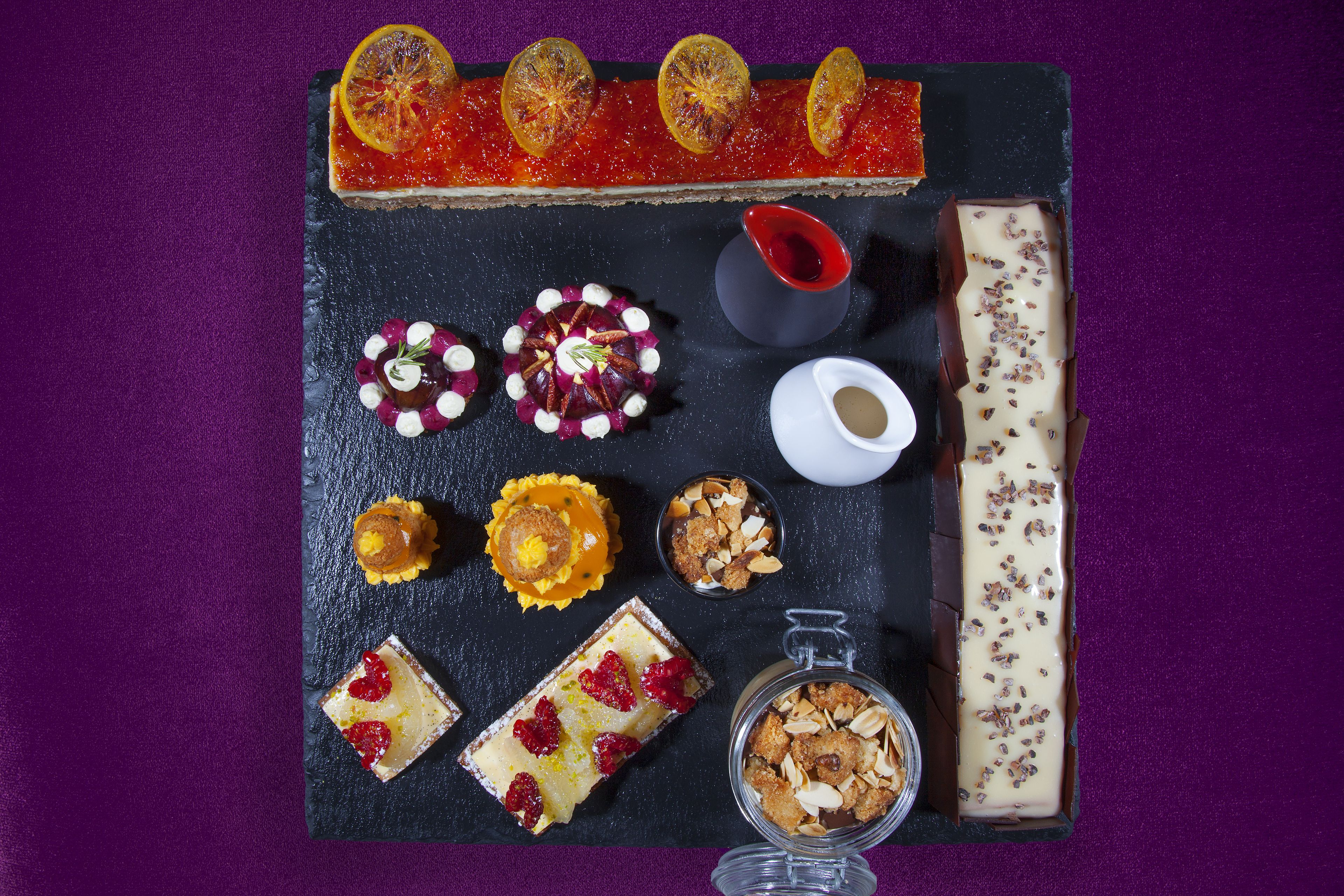 A variety of desserts and pastries on a slate board.