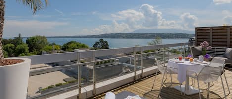 Una terraza con vistas a un lago, mobiliario exterior y una planta en maceta.