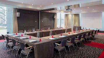 Une salle de conférence équipée d’une longue table, de nombreuses chaises et d’un écran de projection.