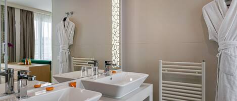 A modern bathroom with two sinks, a towel rack, and a mirror.
