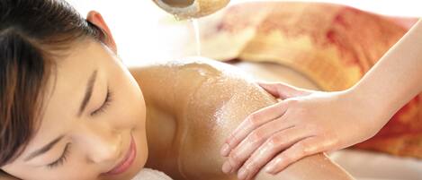 A person receiving a massage with a towel and a bottle of oil.