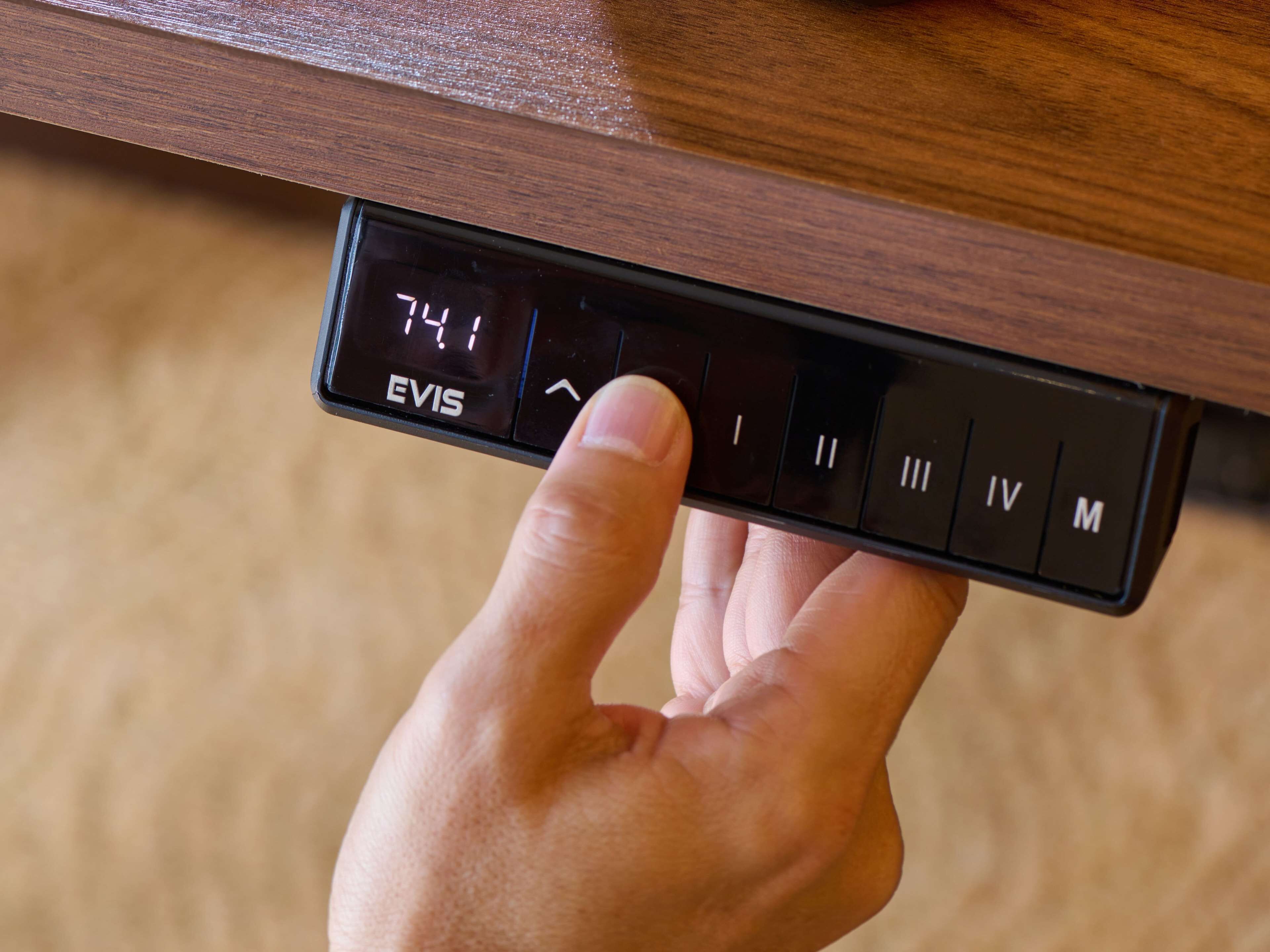 Une main appuyant sur un bouton d’un panneau de commande doté d’un écran numérique affichant « 7,41 » et portant la marque « EVIS ».
