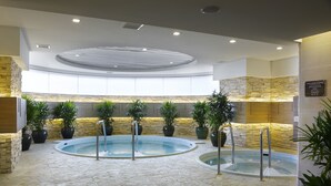 A spa area with a circular hot tub, stone walls, and potted plants.