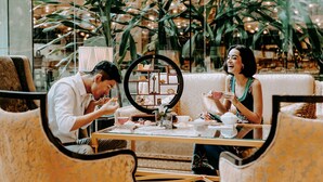 A cozy indoor setting with a round mirror, a table with teacups, and chairs.