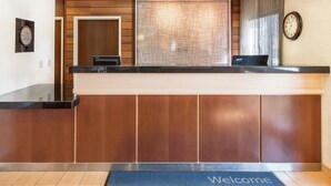 A reception desk with a laptop, a clock, and a welcome mat. - Fairfield Inn & Suites Sioux Falls (Sioux Falls)