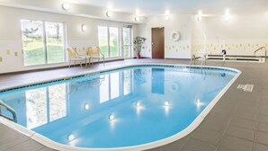 An indoor swimming pool with clear glass walls, a tiled floor, and a door leading outside. - Fairfield Inn & Suites Sioux Falls (Sioux Falls)
