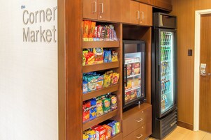 Un mercado de barrio con estantes llenos de aperitivos y una vitrina refrigerada.