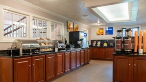 Uma cozinha espaçosa com bancada comprida, máquinas de café e diversas opções de alimentos.