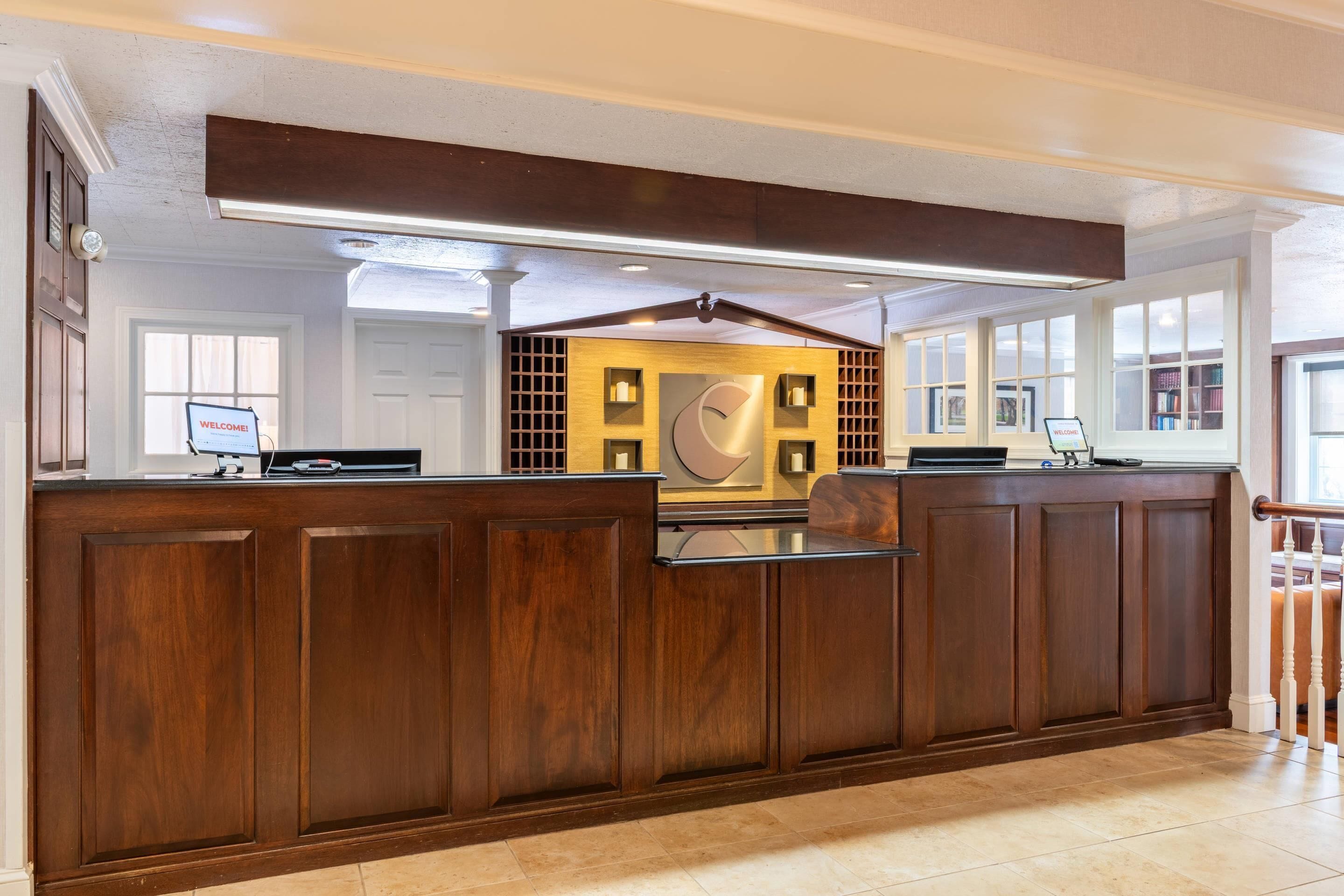 A reception area with a wooden reception desk, a clock, and a welcome sign.